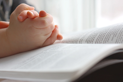 Photo of young child's hands on the Bible