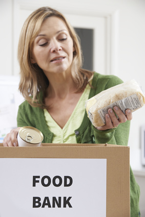 Photo of woman putting a bag of pasta into a box marked 'Food Bank'.