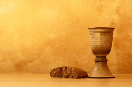 Photo of torn loaf of bread and pottery Communion chalis.