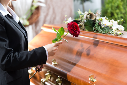 Photo of a person placing a rose on a coffin