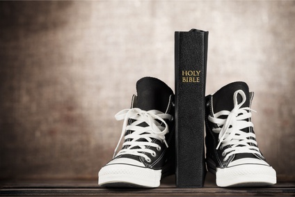 Photo of Holy Bible propped between a pair of converse boots